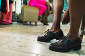 Closeup of legs, black man trying on loafer shoes at clothing store