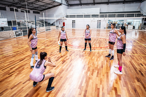Female volleyball team stretching during warm-up on the sports court