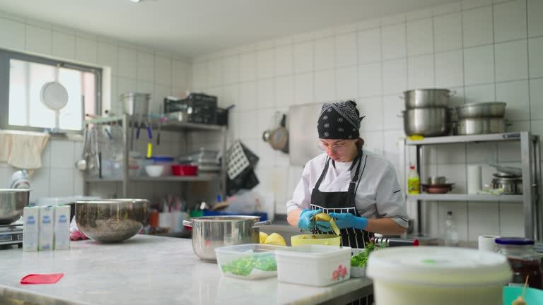 Young woman working and peeling potatoes in commercial kitchen