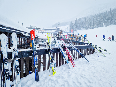 Hemsedal, Norway - March 16, 2023: Skis standing at the rest area. View over ski resort with slopes, chair lifts and majestic snowy mountains during winter.