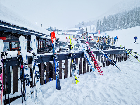 Hemsedal, Norway - March 16, 2023: Skis standing at the rest area. View over ski resort with slopes, chair lifts and majestic snowy mountains during winter.