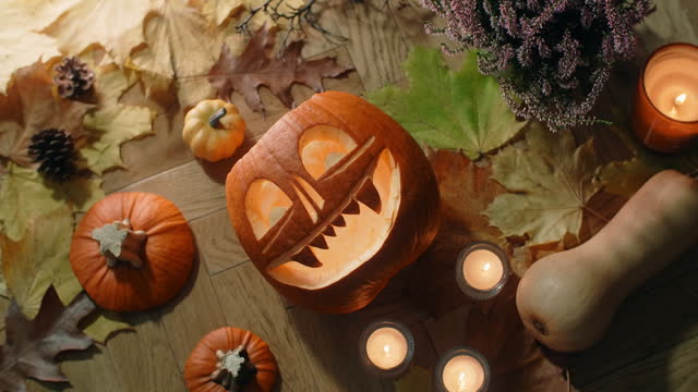 Halloween decorated composition with pumpkin face, autumn leaves and lightened candles, 4k 60p Prores HQ 10 bit