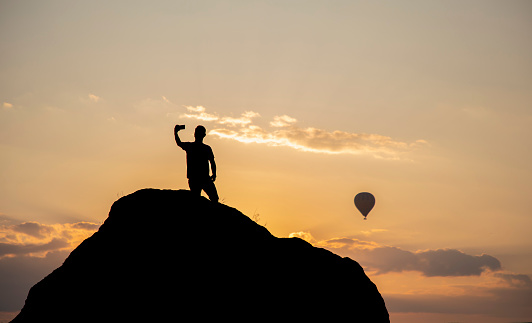 Silhouette of a man taking a selfie on a rock in the Cappadocia landscape