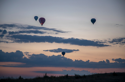 Traveler on mountain peak at sunset, hot iar balloon flying away