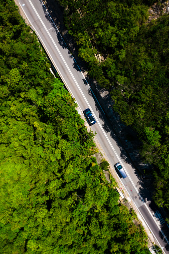 Aerial top view of country road in green summer forest. Rural landscape in Hong Kong