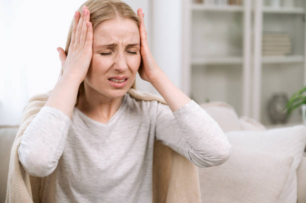 istock Annoyed woman touching head and suffering from migraine 1570448093