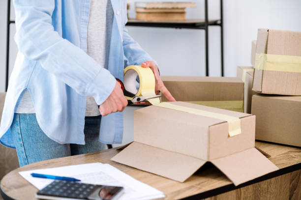 istock Business owner using sticky tape scotch and scissors for packing box 1570451270