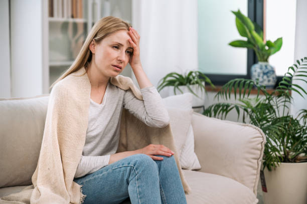 istock Sick woman sitting on couch, feeling cold and having headche 1570458942