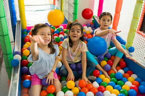 Fun happy group of kids laughing in the indoor playground while enjoying playing a gme in the ball pit