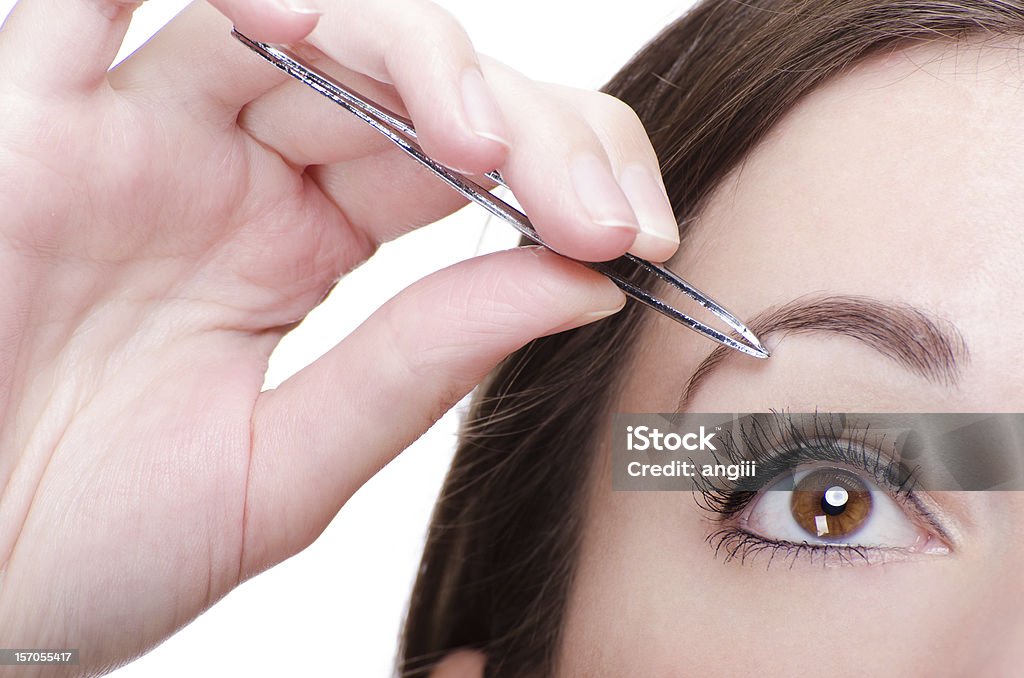 Young Woman Tweezing Her Eyebrows Young Woman Tweezing Her Eyebrows isolated on white 20-29 Years Stock Photo