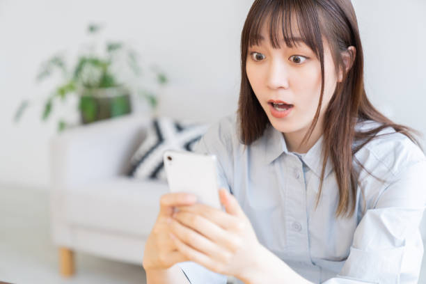 attractive Asian woman using a smart phone,surprised stock photo
