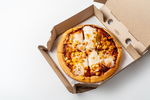 Pizza in a cardboard box on a white background. View from above. Pizza delivery.