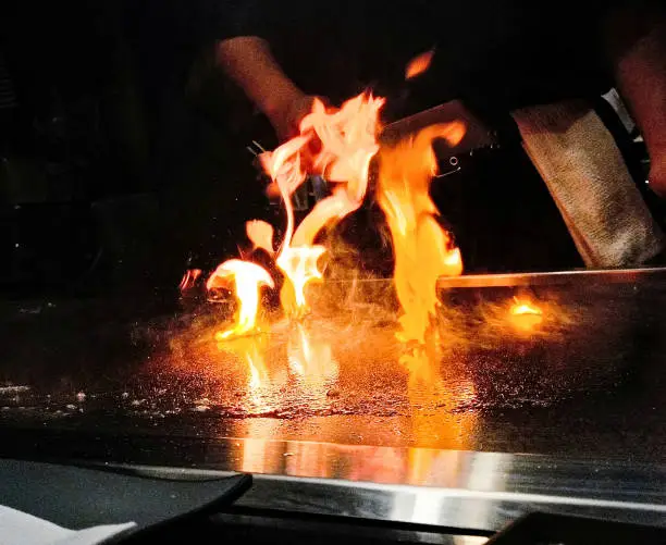 A teppanyaki chef making fire with oil at a Japanese restaurant