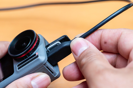 Close up of male hands charging action camera with USB C cable