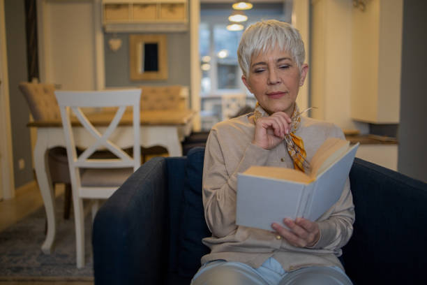 istock Happy woman reading book at home 1570671032