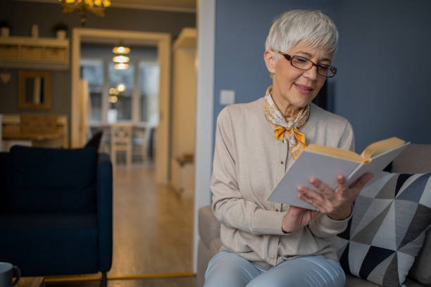 istock Happy woman reading book at home 1570671053