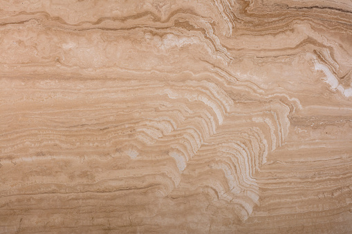 Unique texture of natural travertine, soft pattern of beige and brown wavy layers.