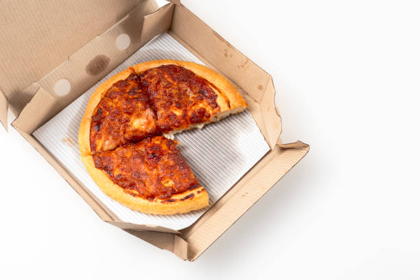 istock Margherita Pizza in a cardboard open delivery box on a white background. A piece is missing from the box. Top view. 1570686052