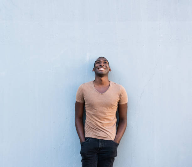 istock cool young African American guy leaning against gray wall and looking up 1570687680