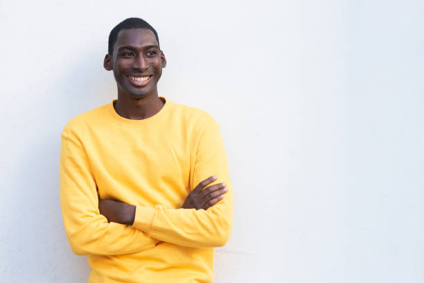 istock smiling young black man with arms crossed by white wall 1570688790