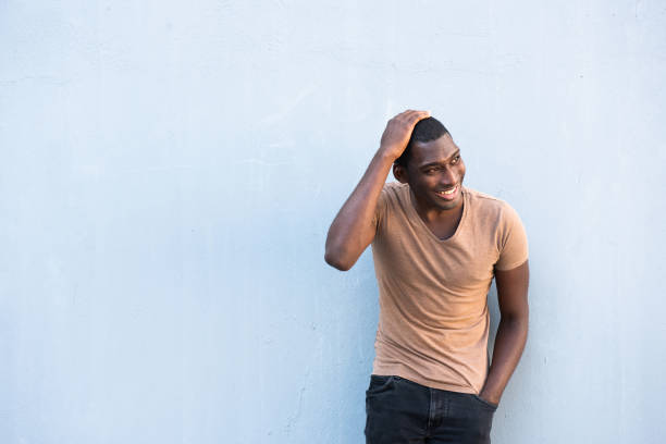 istock smiling young black man against gray wall and hand on head 1570688796