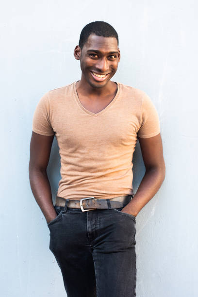 istock handsome young black man smiling and leaning against gray wall 1570688819