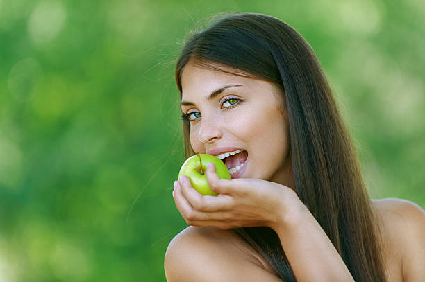 istock funny young woman bites off an green apple 157069573