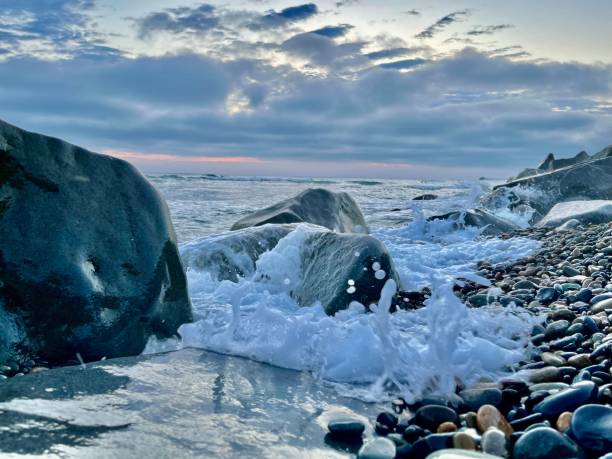 istock Sea foam splashes on beach stones and dark sky 1570731876
