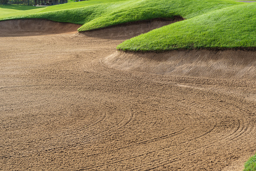 View of the green rolling landscape and bunkers or sand traps at Golf course. The golf field is made in 3D.