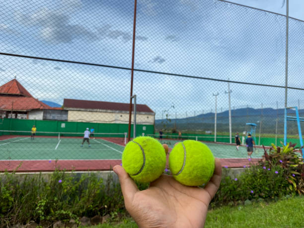 istock Hands holding two tennis balls 1570768555