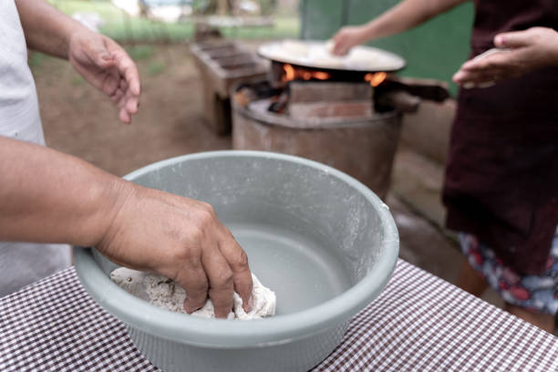 пожилая латиноамериканка берет тесто, чтобы приготовить кукурузные лепешки - guatemalan culture central america mother traditional culture стоковые фото и изображения