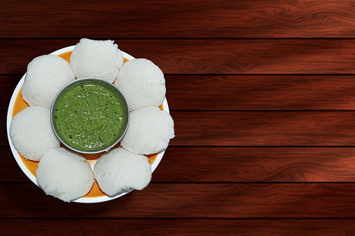 Idly is a popular Indian dish served in a bowl with green chutney. Top view