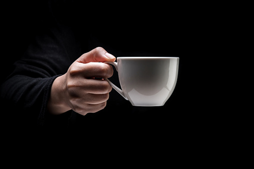 The image of a woman holding a coffee cup, on black background.