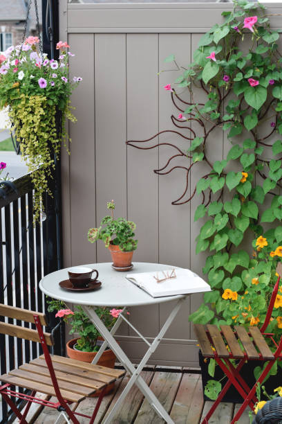 istock Apartment balcony with a bistro set, book and coffee cup surrounded by plants 1570823601