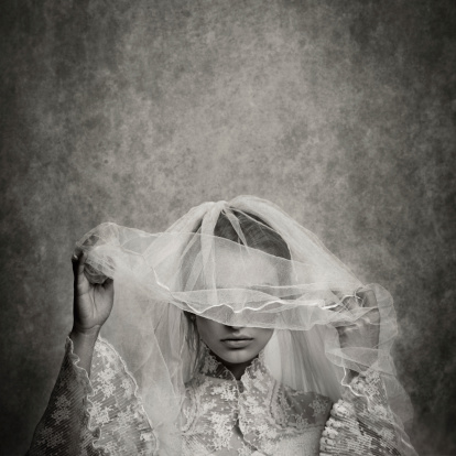 ghostly bride raising her veil - toned image, added grain, texture, vignetting