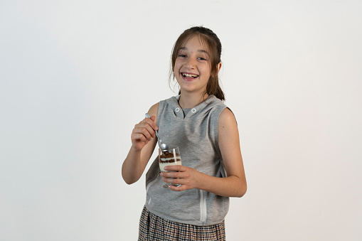 Portrait of a girl on a white background. Girl eating dessert from bowl.