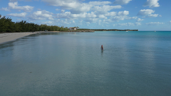 Lofty clouds above her and white sand beach, Eleuthera