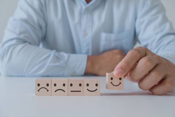 Customer service evaluation and satisfaction survey concept. The customer's hand picked the happy face smile face icon on wooden cube block on white background.