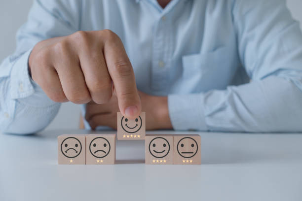 istock Customer service evaluation and satisfaction survey concepts. The customer's hand picked the happy face smile face with star icon on wooden cube block on white background. 1570911927