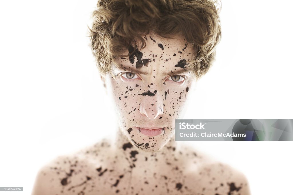 High Key Portrait of Stern Man Covered in Paint Bright portrait with high key background and light spilling onto subject's shoulders. Man is glaring at the camera with a stern expression, covered in paint. Image has a shallow depth of field, focus is on the eyes. Shoulders are out of focus. Adult Stock Photo