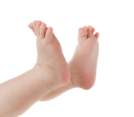 Mother’s hands holding new born baby’s feet