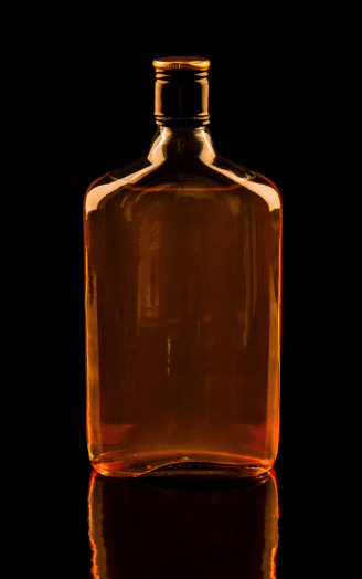 Isolated with clipping paths single bottle of whisky with reflection. Warm luxury colors image