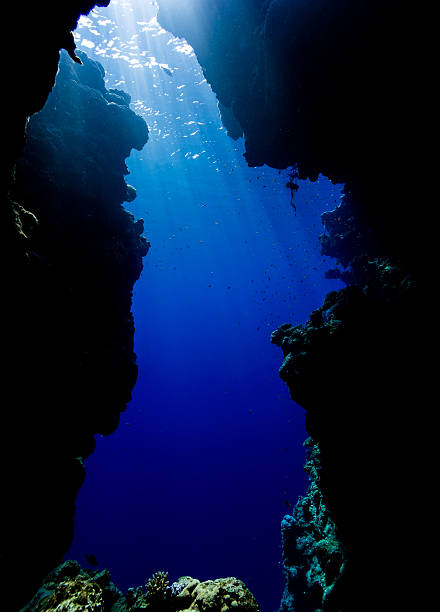 Sun rays filter down through an underwater cave exit Sun beams filtering down from the surface through blue water at the exit from a shallow water sea cavern in the northern Red Sea dahab photos stock pictures, royalty-free photos & images