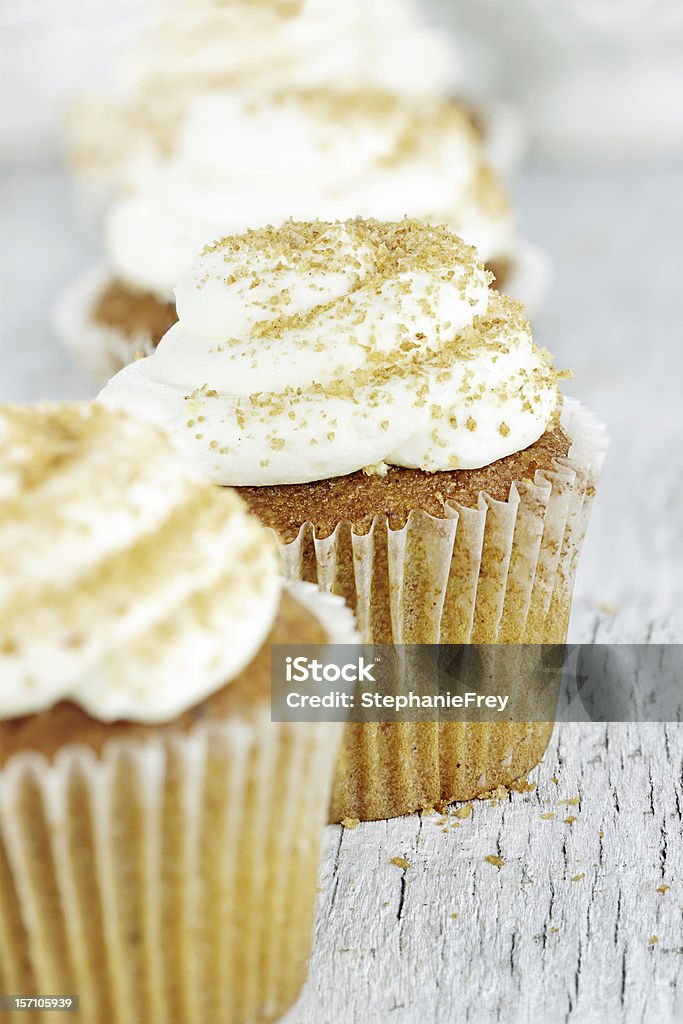 Pumpkin Spice Cupcake with Cream Cheese Icing Pumpkin spice cupcakes frosted with cream cheese icing and sprinkled with brown sugar. Extreme shallow depth of field with selective focus on center cupcake. Baked Stock Photo