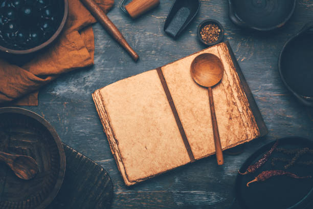 istock Empty menu or cookbook and kitchen utensils on wooden table, vintage style 1571065390