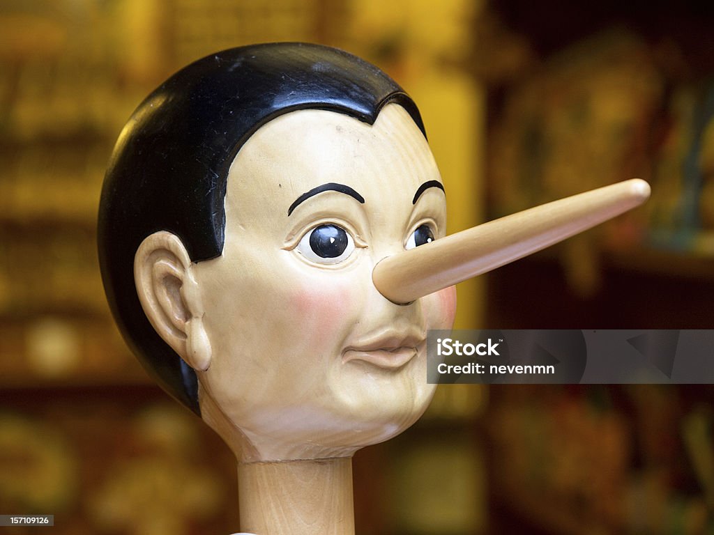Wooden toy Pinocchio head with long nose on stick Wooden pinocchio doll with his long nose. Pinocchio Stock Photo