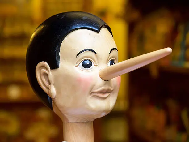 Photo of Wooden toy Pinocchio head with long nose on stick