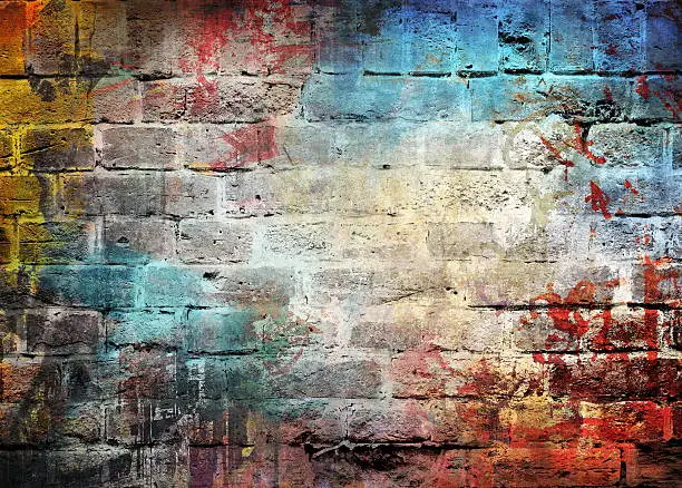Photo of Brick wall with letters and different colors splattered on