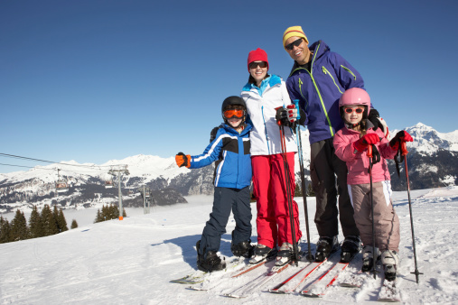 Family wearing colorful snow gear on a mountain while skiing
