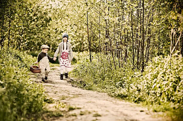 Hansel and Gretel walking on forest path, looking for mushrooms and wild berries.